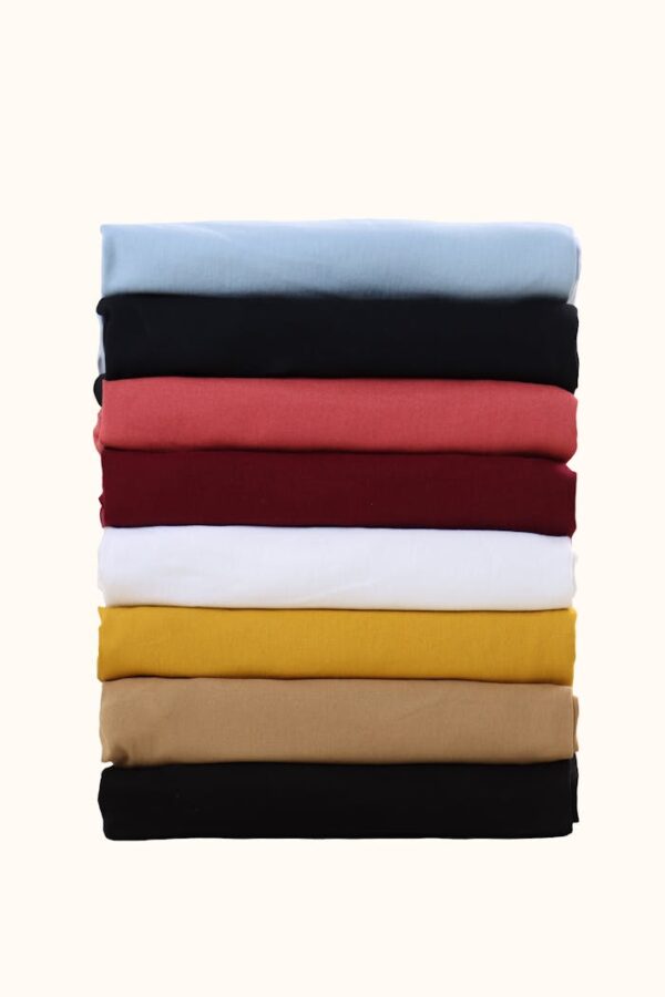 A neatly stacked assortment of colorful fabric swatches on a plain background.