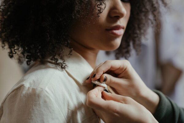 A detailed close-up of a tailor adjusting a shirt on a model with curly hair, showcasing precision.