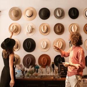 Elegant hat display in a fashion boutique with two stylish adults browsing.