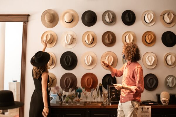 Elegant hat display in a fashion boutique with two stylish adults browsing.