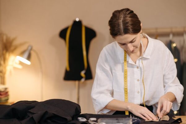 A fashion designer measuring fabric with a tape measure in a design studio setting.