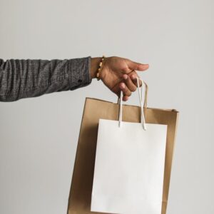 A stylish hand extends with paper shopping bags, symbolizing a seamless online shopping experience.